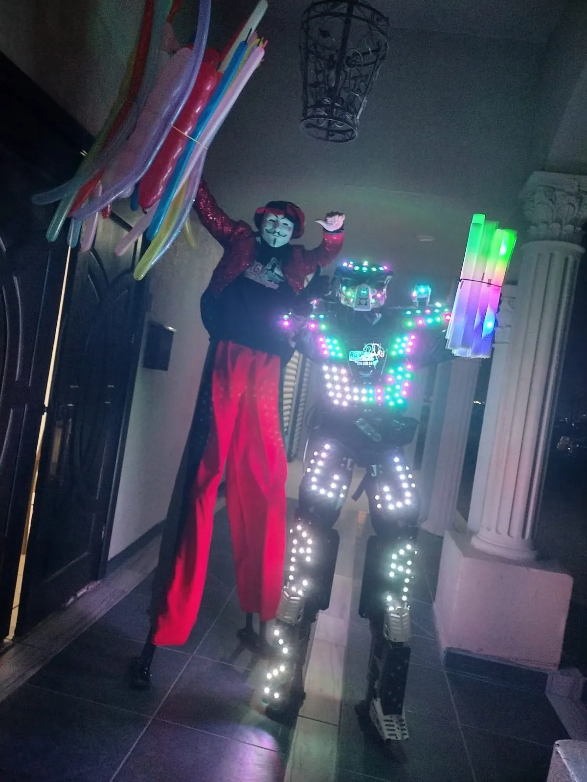 Robot LED y personaje en zancos